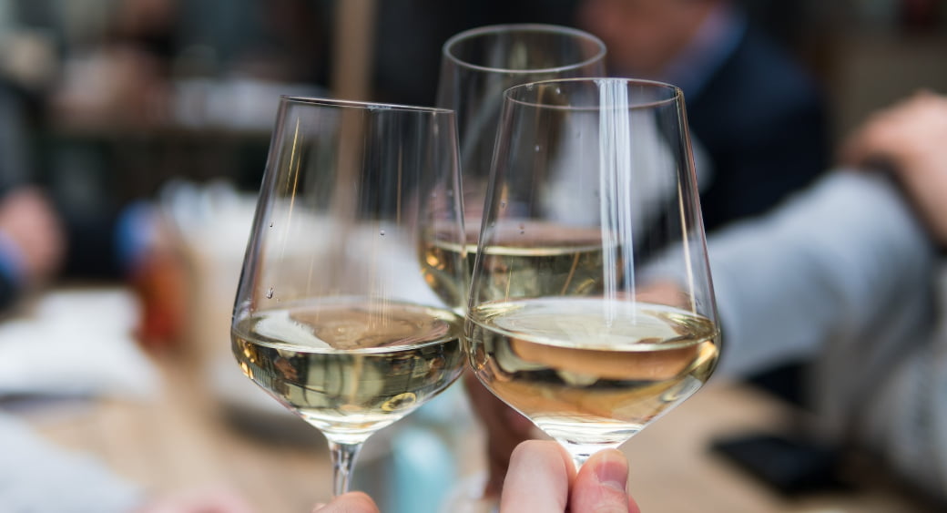 three wine glasses clinking together as a cheers. Photo by Matthieu Joannon, Unsplash